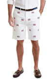 A pair of men's white shorts with embroidered American flags on them, paired with a navy polo shirt and a surcingle belt.